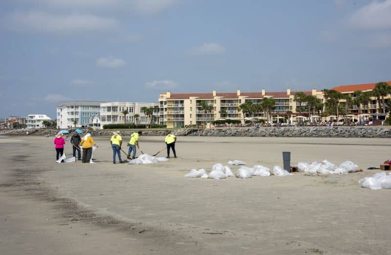 Une équipe de nettoyage du littoral remplit lundi des sacs de sable huilé à retirer de la plage près du parc Massengale