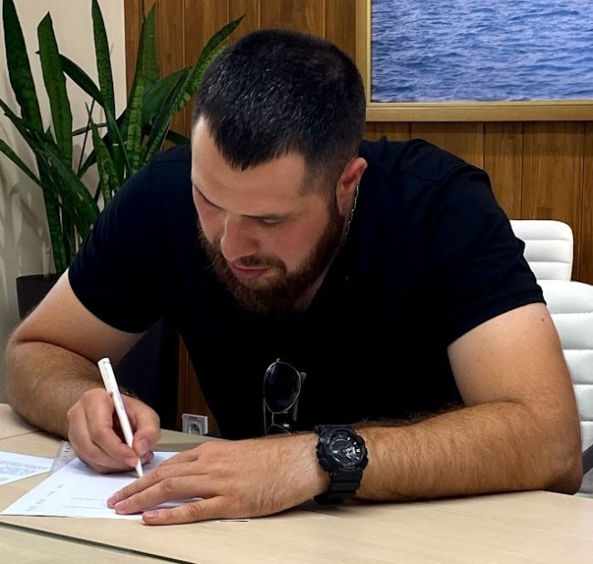 Yevgeniy Nikolov signe l'accord d'indemnisation final au bureau du MTWTU (Crédit : MTWTU)​